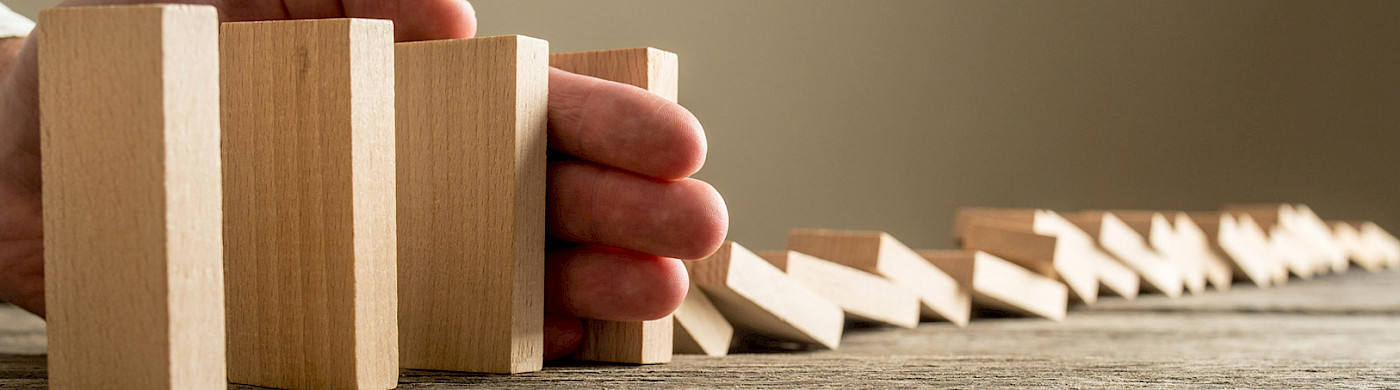 Krisen / Krisenintervention Hand die umfallende Dominosteine aufhält - ©